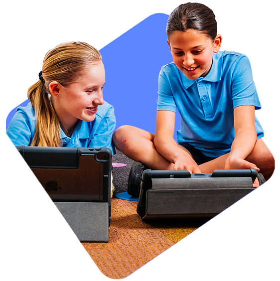 A young child and her teacher smiling while interacting with a mobile device.